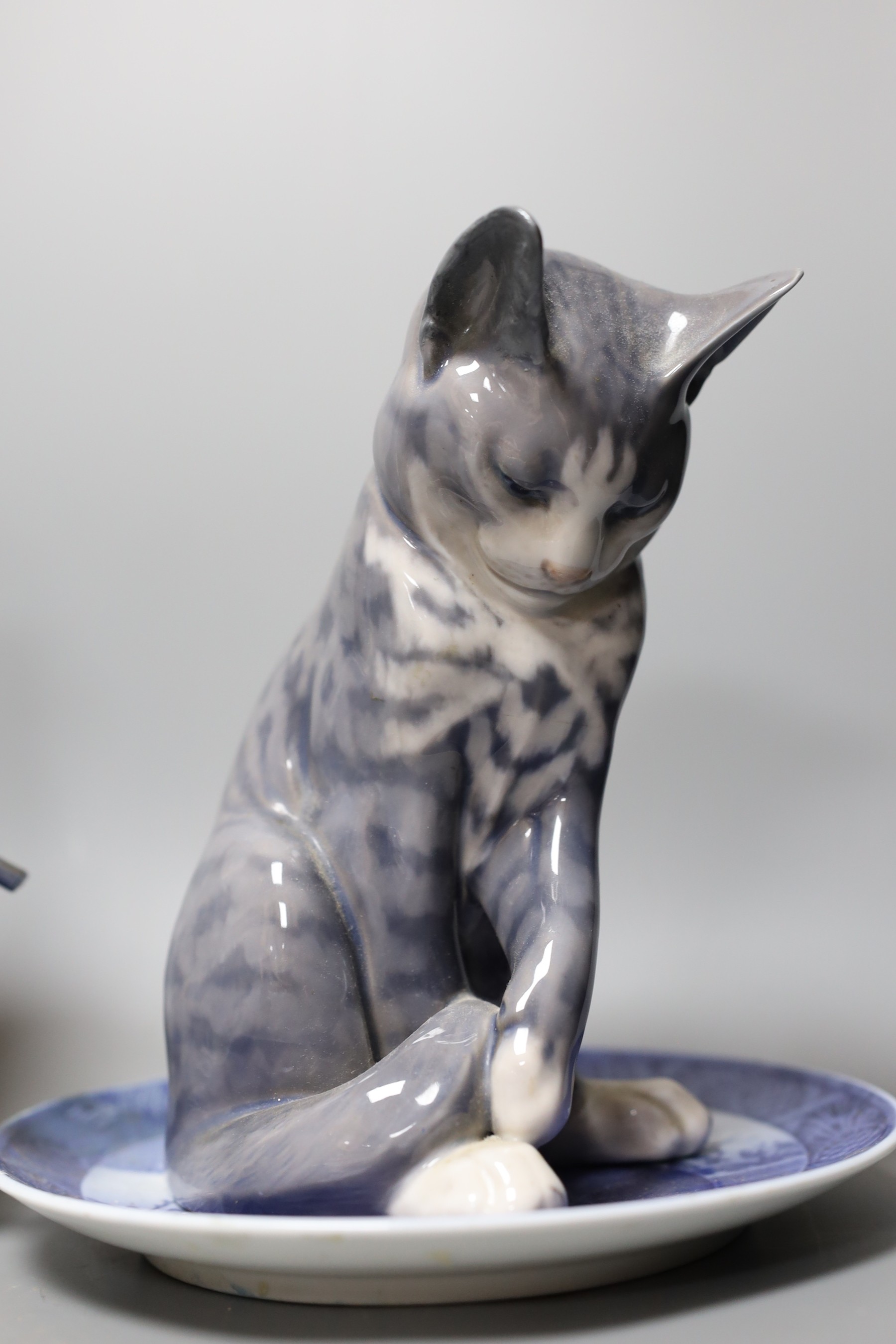 Eight pieces of Royal Copenhagen, to include a seated cat 340, Christmas Rose and Cat plate, a seated farm boy 4539, a young footballer 5657, two floral vases 2630 2289 and 57/251 K.P, a seated huntsman with dog 1087, an